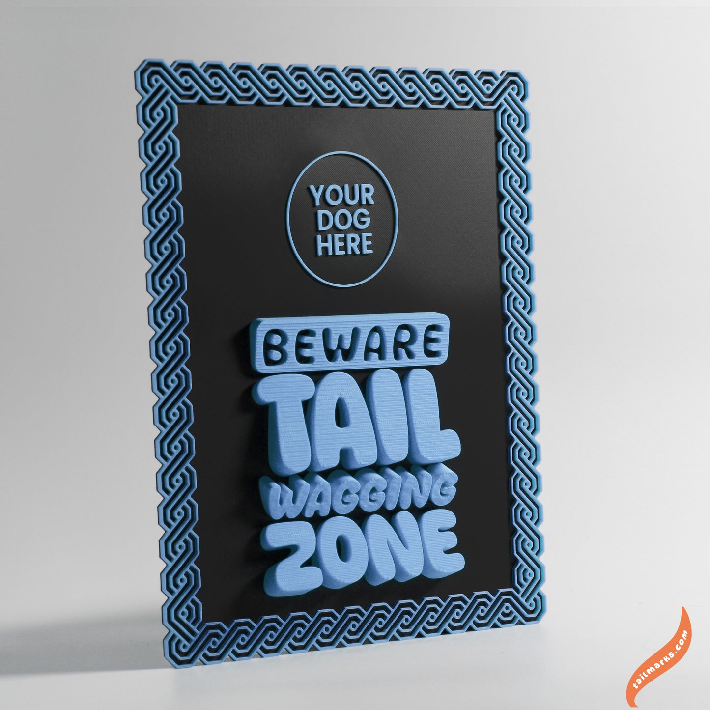 Decorative sign with text 'Beware Tail Wagging Zone' with a maya frame on a black background with blue border.