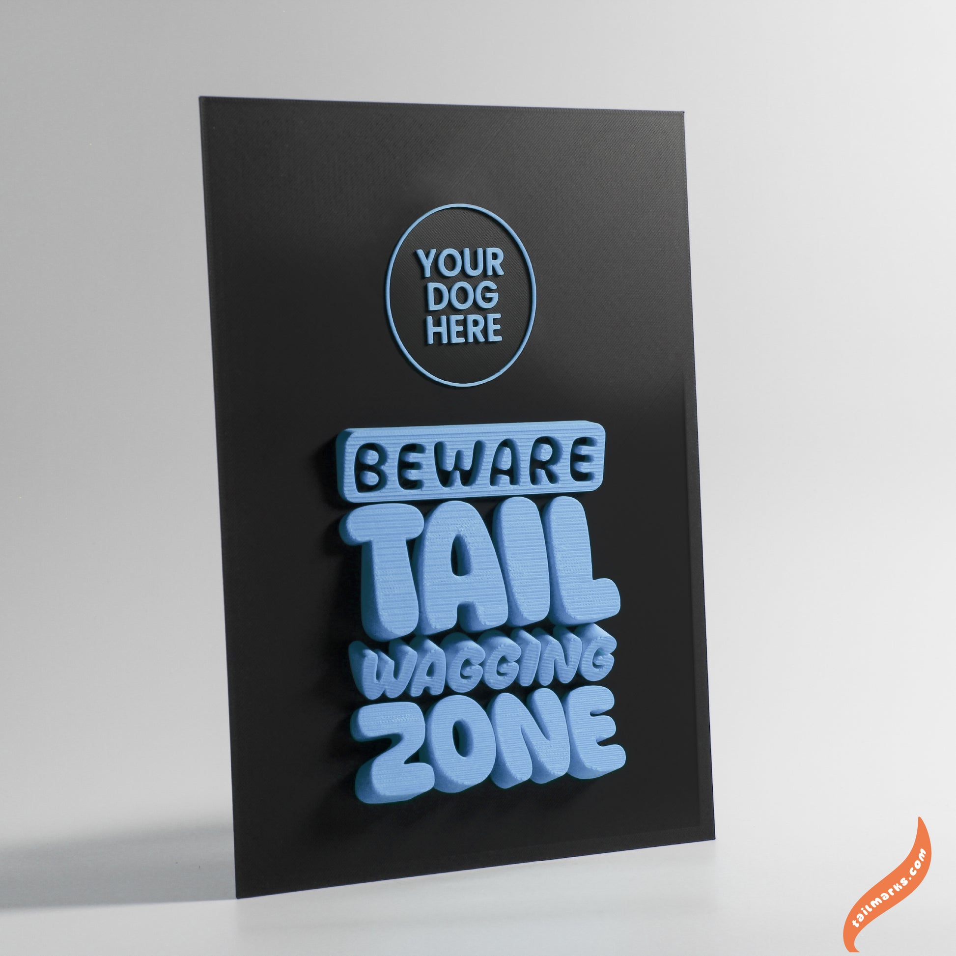 Black sign with blue text 'Beware Tail Wagging Zone' on a white background