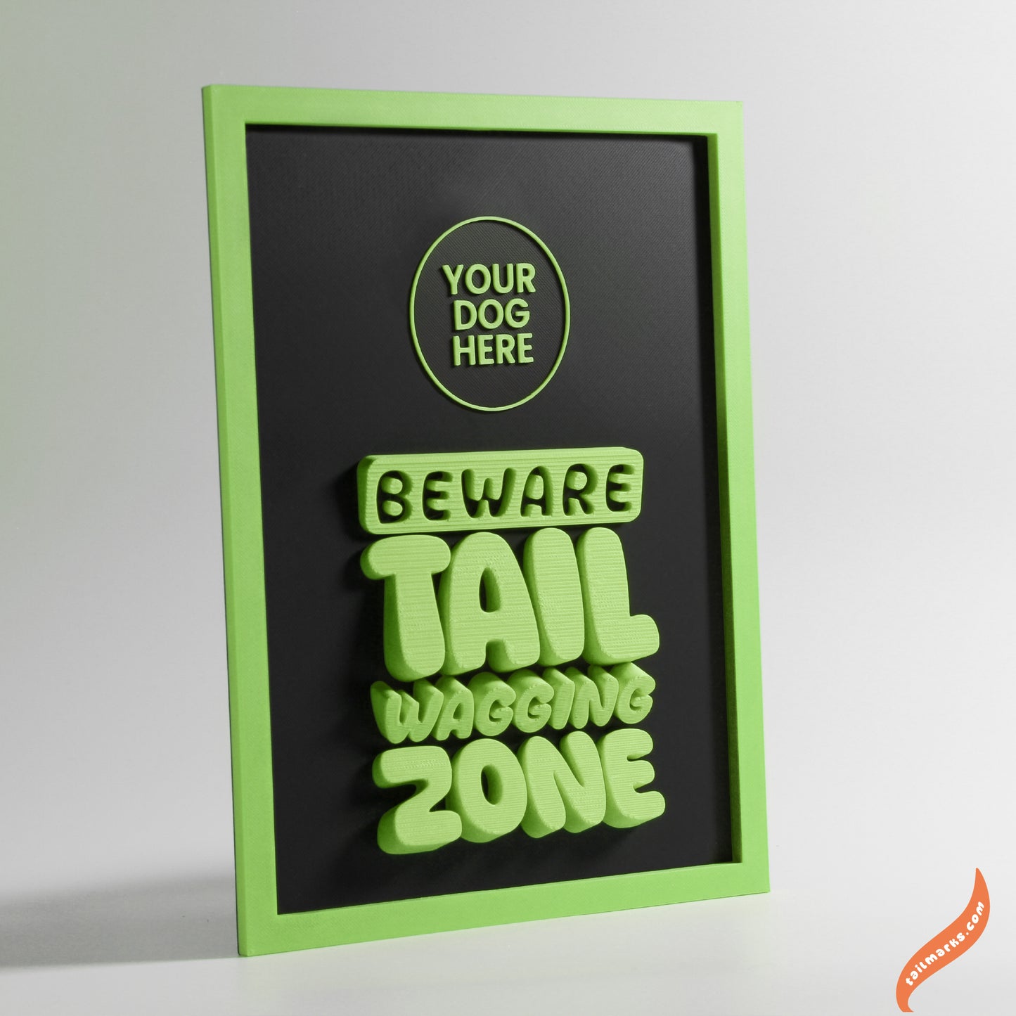 Decorative sign with green text 'Beware Tail Wagging Zone' on a black background with green bold frame.
