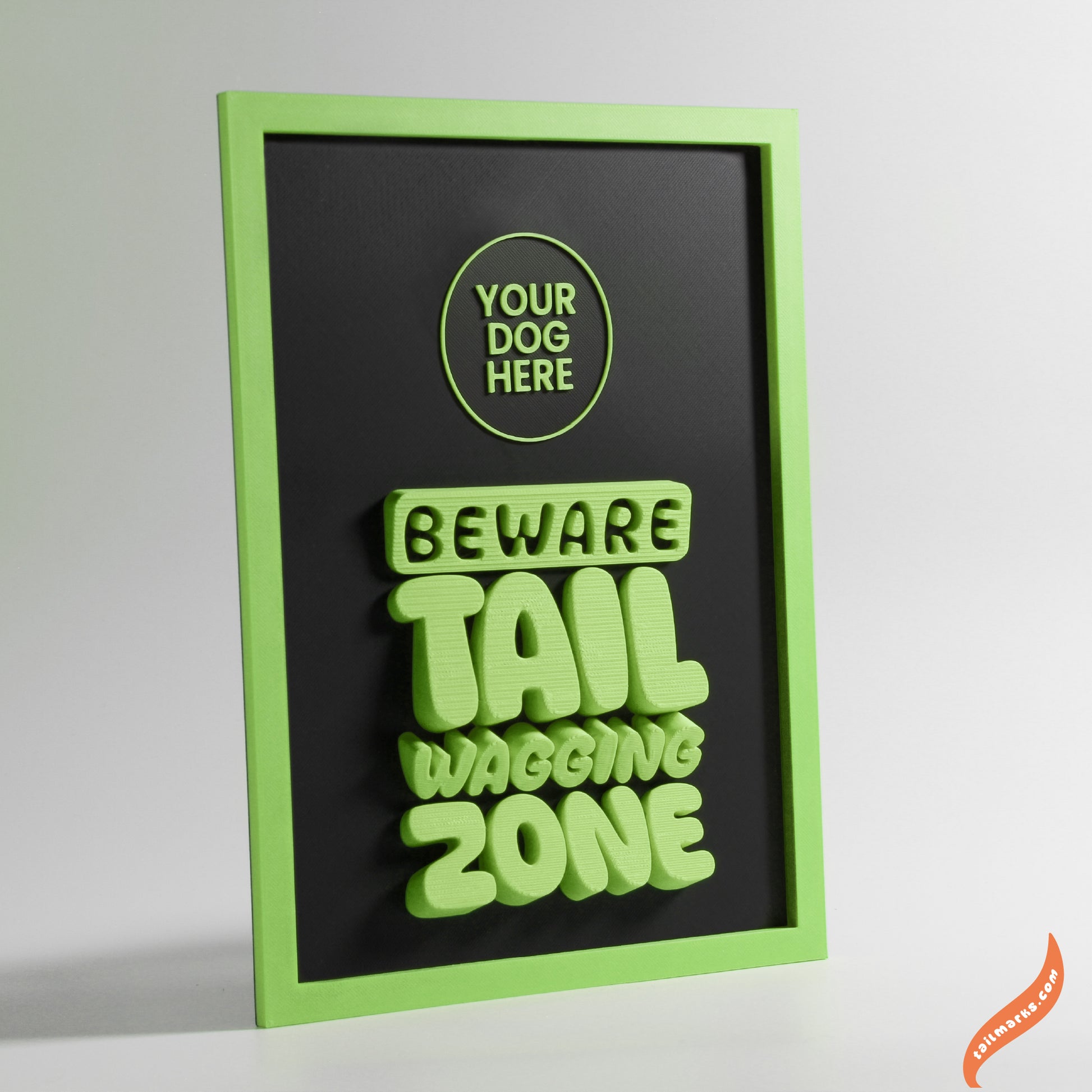Decorative sign with green text 'Beware Tail Wagging Zone' on a black background with green bold frame.