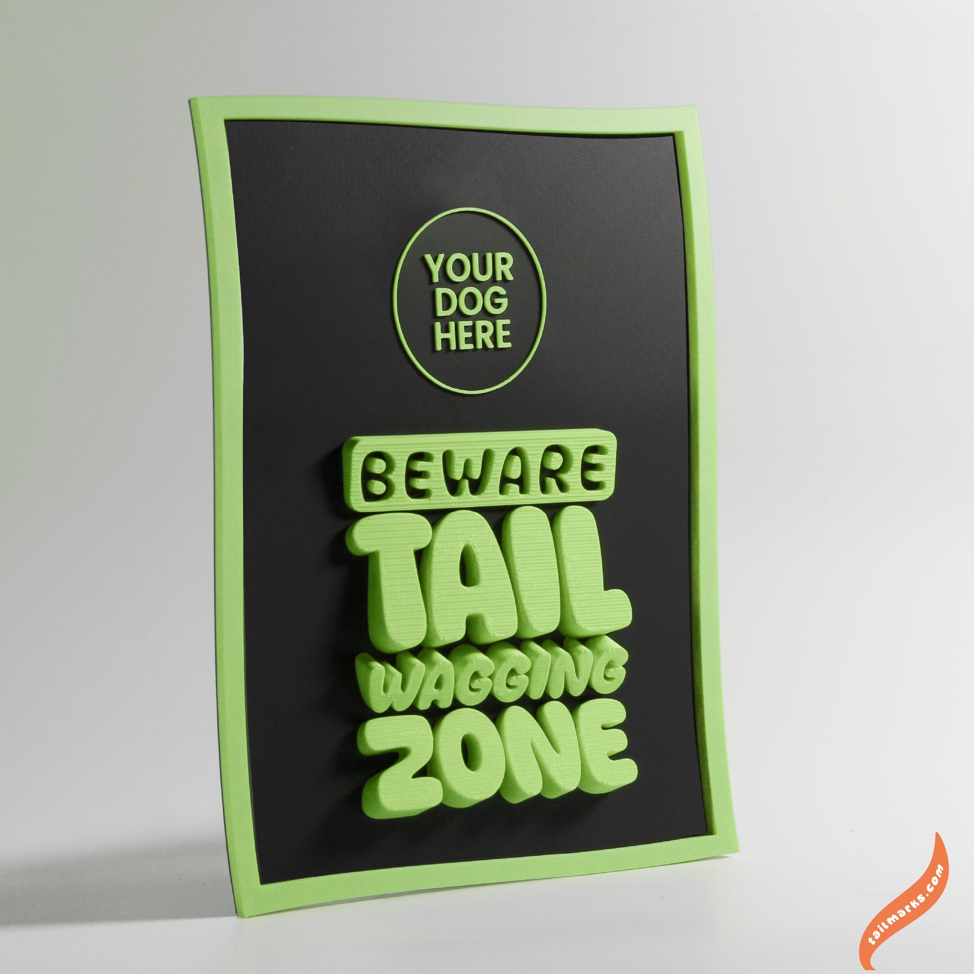Decorative sign with text 'Beware Tail Wagging Zone' and a green waggy frame on a black background.