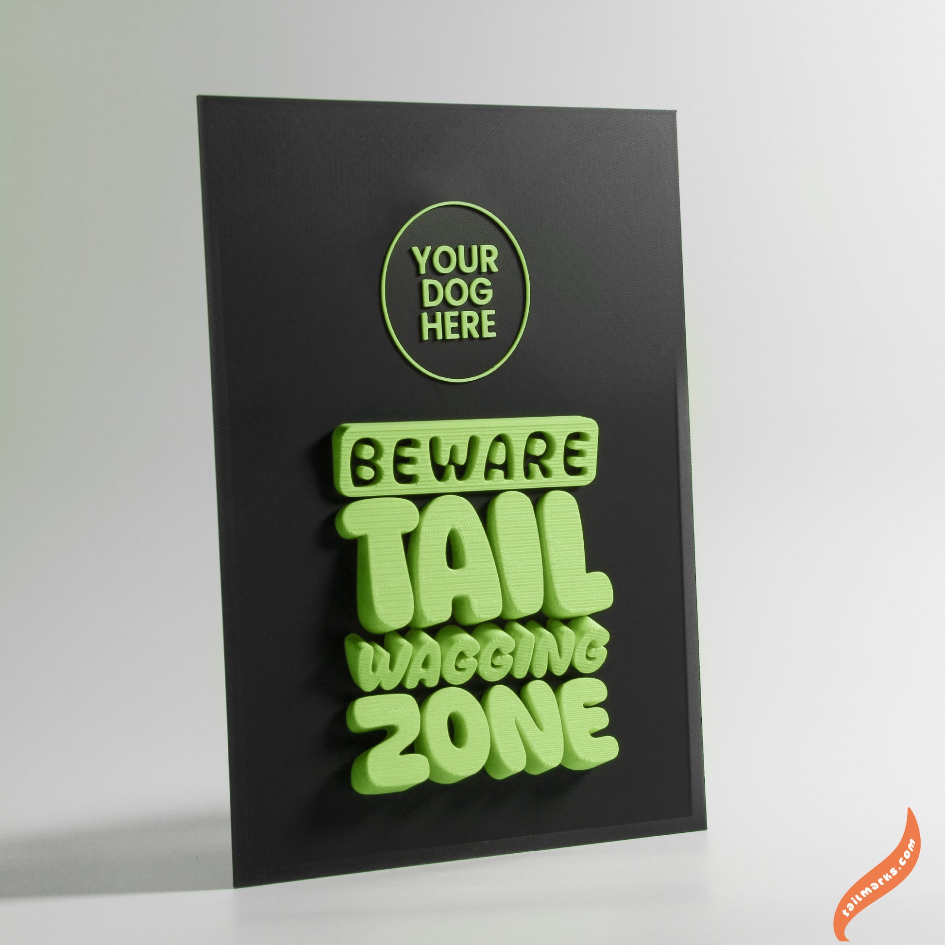 Black sign with green text 'Beware Tail Wagging Zone' on a white background