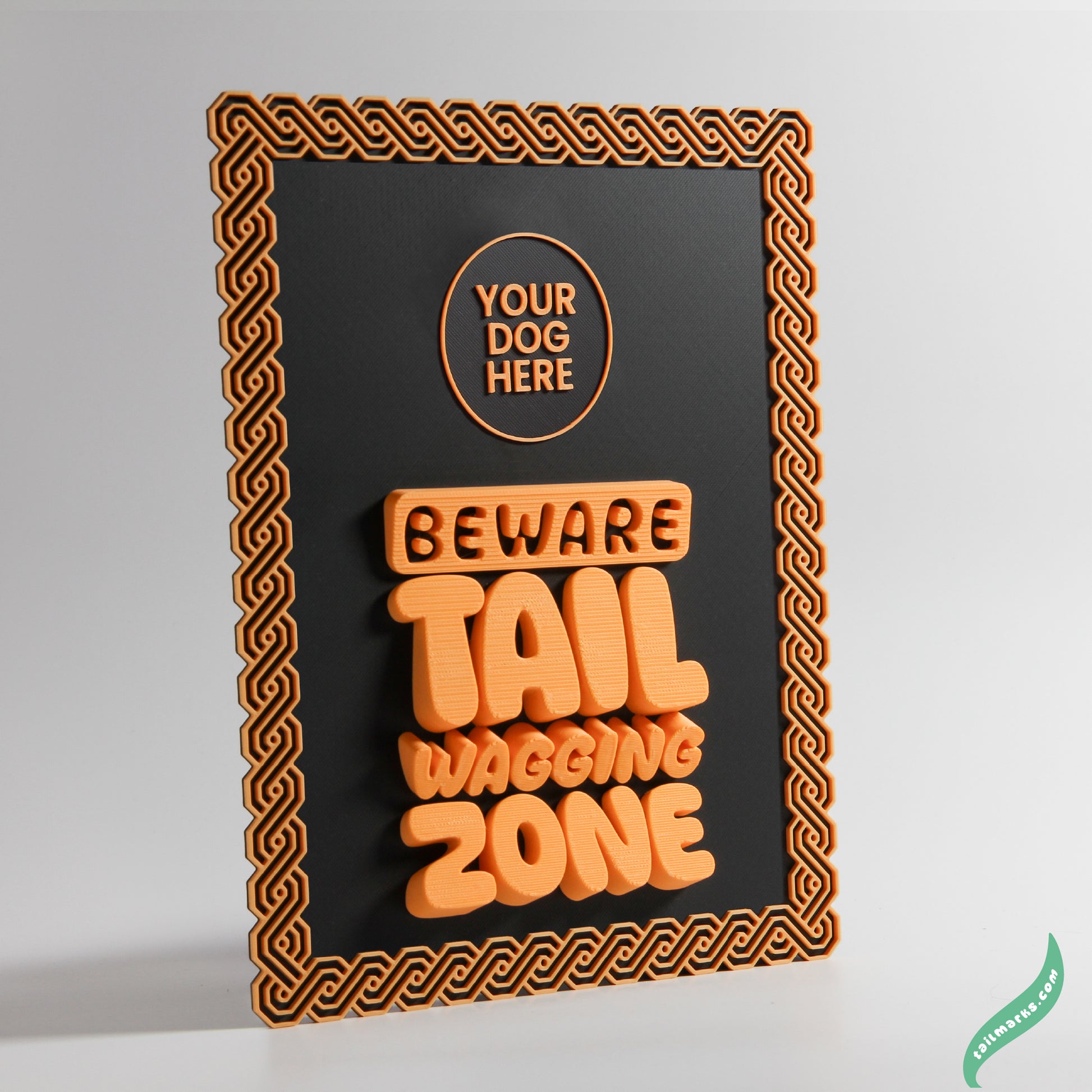 Decorative sign with orange text 'Your Dog Here Beware Tail Wagging Zone' on a black background and a maya frame
