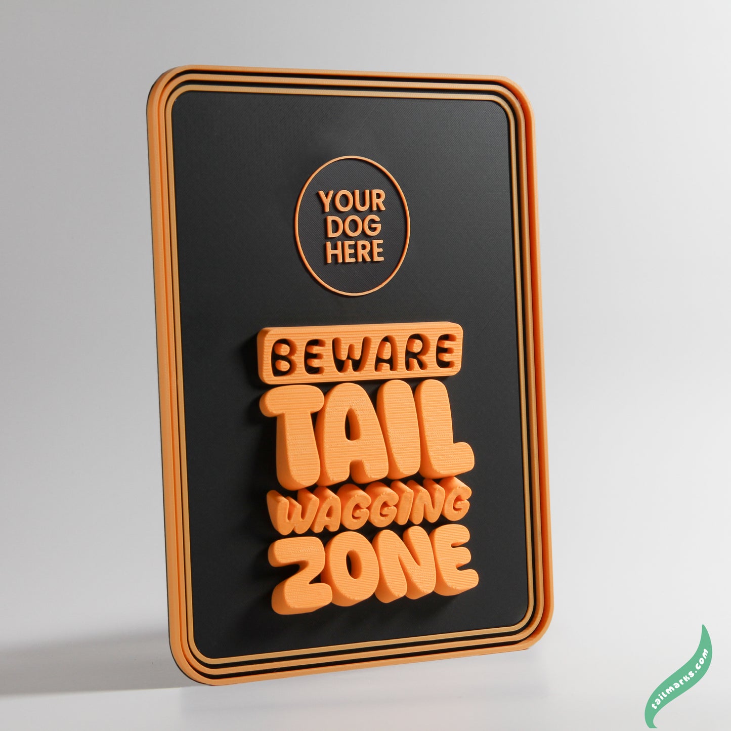 Decorative sign with text 'Beware Tail Wagging Zone' on a black background with a round frame