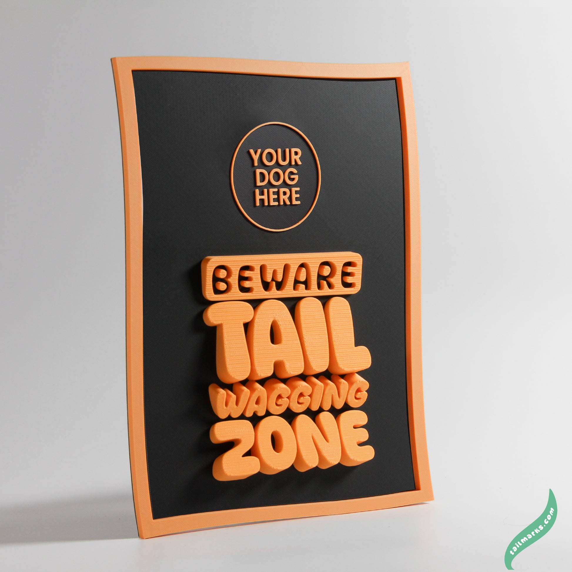 Decorative sign with 'Beware Tail Wagging Zone' text on a black background with orange waggy frame