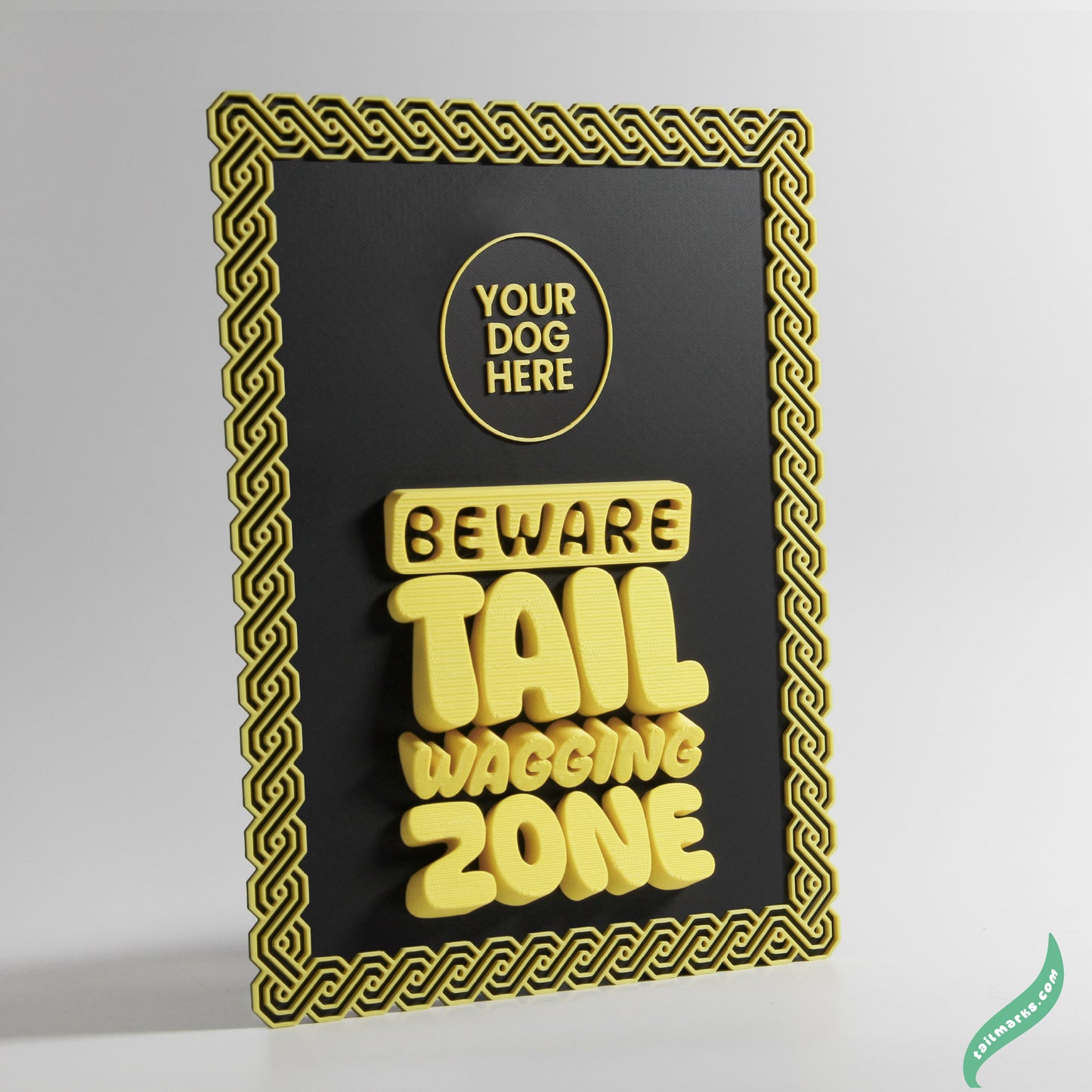 Decorative sign with 'Beware Tail Wagging Zone' yellow text on a black background with yellow maya frame.