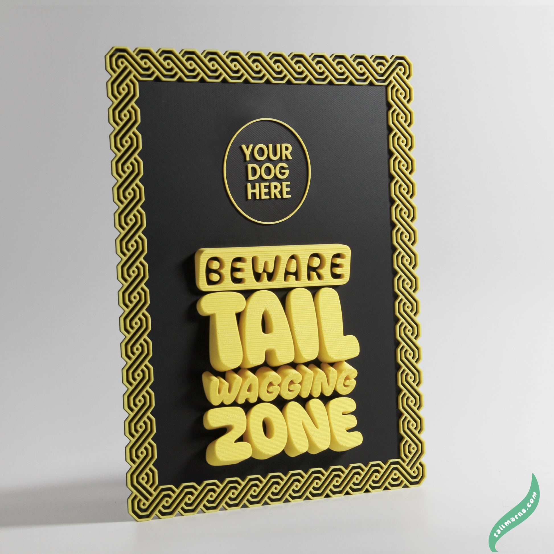 Decorative sign with 'Beware Tail Wagging Zone' yellow text on a black background with yellow maya frame.