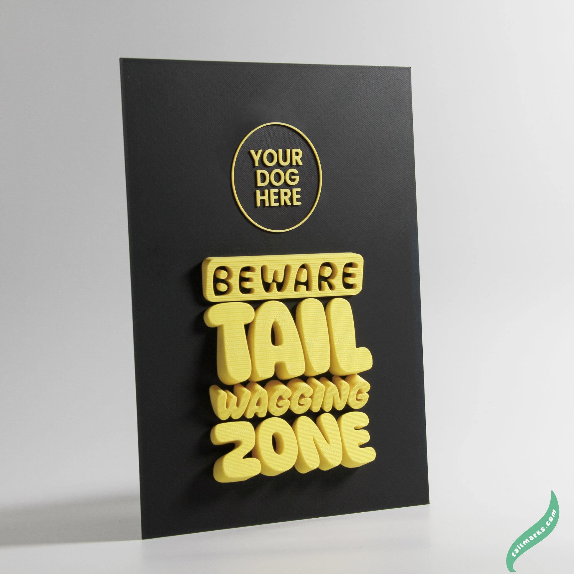 Black sign with yellow text 'Beware Tail Wagging Zone' on a white background